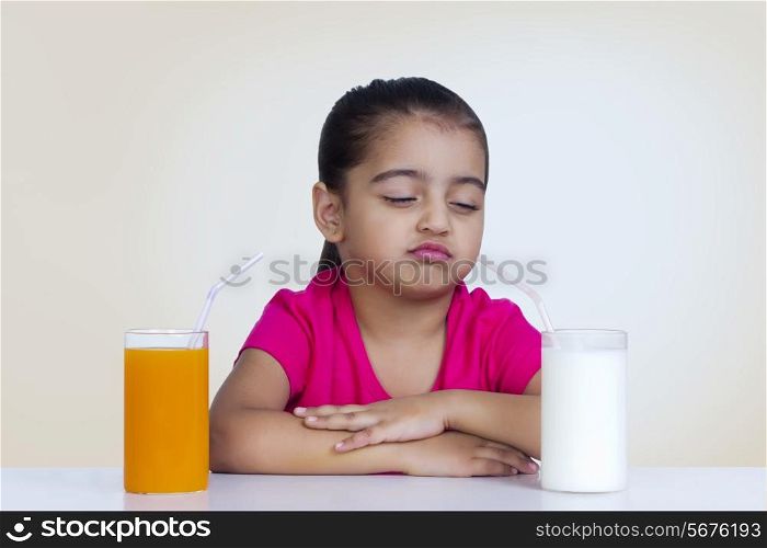 Confused girl choosing between milk and orange juice against colored background