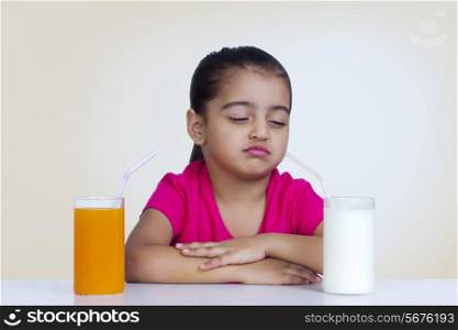 Confused girl choosing between milk and orange juice against colored background