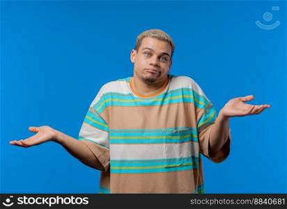 Confused man, shoulders up - can’t help, makes gesture of I dont know. Difficult question, guilty reaction, puzzled guy on blue background. High quality photo. Confused man, shoulders up - can’t help, makes gesture of I dont know. Difficult question, guilty reaction, puzzled guy on blue background.