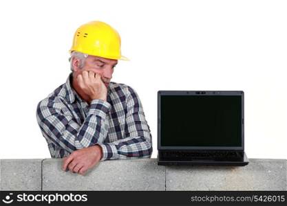 Confused middle-aged builder looking at laptop