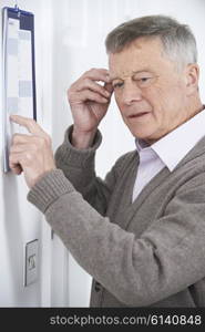 Confused Senior Man With Dementia Looking At Wall Calendar