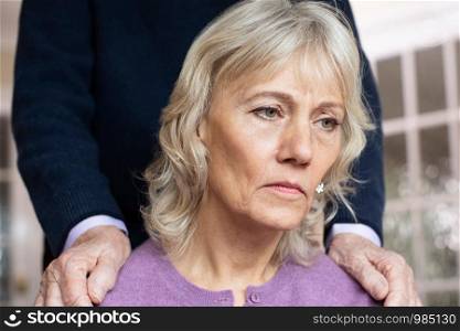 Confused Senior Woman Suffering With Depression And Dementia Being Comforted By Husband