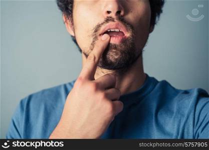 Confused young man touching his lip with his finger