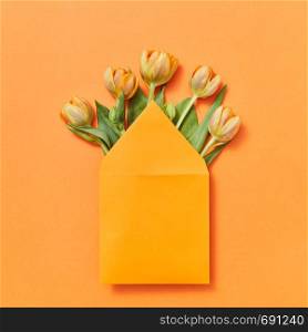 Congratulation post card of handcraft envelope of yellow tulips on an orange background wiyh lace for text. Flat lay.. Mock up envelope with yellow tulips on an orange background.