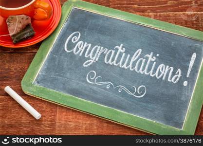 Congratulations! Text on a slate blackboard with chalk and cup of tea