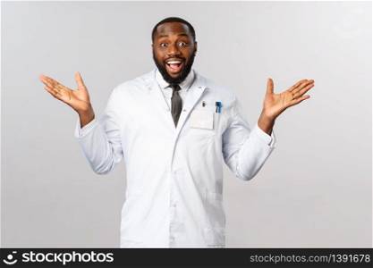 Congratulations, you cured. Portrait of happy and relieved, smiling african-american male doctor in white coat, spread hands sideways rejoicing, look surprised and pleased patient get well.. Congratulations, you cured. Portrait of happy and relieved, smiling african-american male doctor in white coat, spread hands sideways rejoicing, look surprised and pleased patient get well