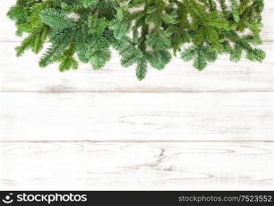 Coniferous trees branches over bright wooden texture. Christmas decoration. Winter holidays background