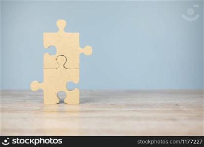 connecting couple puzzle piece, wood jigsaw on table background. Business solutions, mission, success, goals and strategy concepts