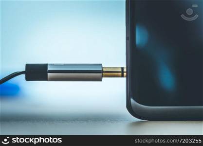 Connection 3.5mm audio jack to a black mobile phone.