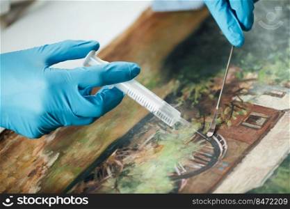Conservator restoring an old oil painting, revitalizing canvas with syringe . Oil Painting Restoration Process