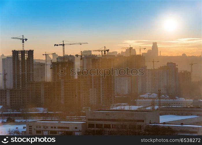 Constraction site with industrial cranes in city at sunset. Constraction site with cranes