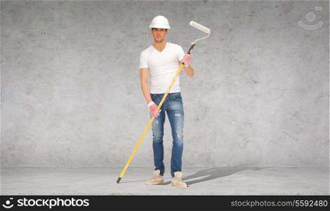 construction and building concept - handsome painter in helmet with paint roller over concrete wall