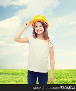 construction and people concept - smiling little girl in protective helmet looking up