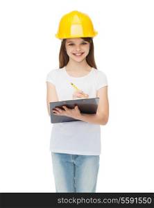 construction and people concept - smiling little girl in protective helmet with clipboard
