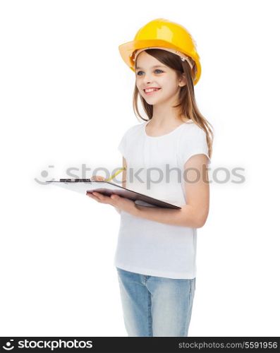 construction and people concept - smiling little girl in protective helmet with clipboard