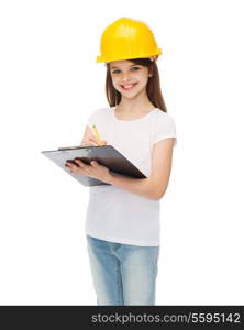 construction and people concept - smiling little girl in protective helmet with clipboard