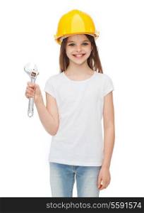 construction and people concept - smiling little girl in protective helmet with wrench