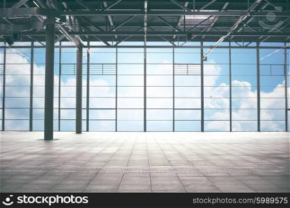 construction, architecture and building concept - airport terminal empty room over blue sky and clouds background