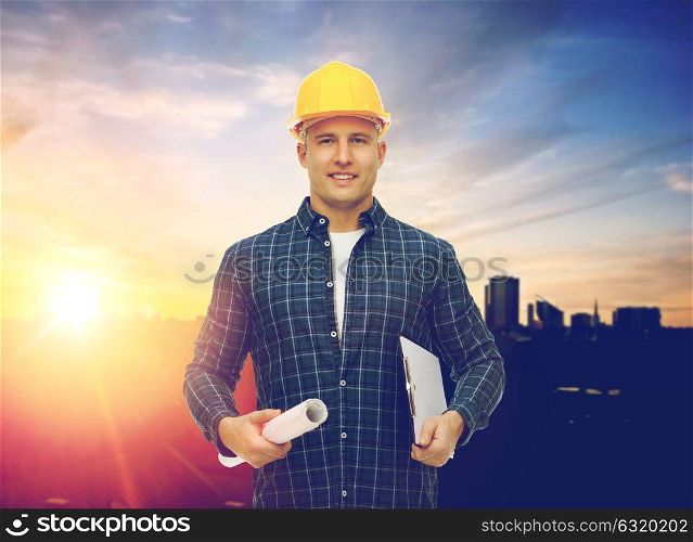 construction, building and people concept - male builder or foreman in yellow hard hat with blueprint and clipboard over city background. builder in hard hat with blueprint and clipboard