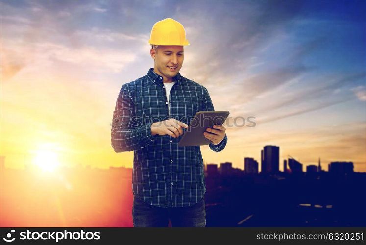construction, building and technology concept - smiling male builder or manual worker in yellow hard hat with tablet pc computer over city background. male builder in yellow hard hat with tablet pc
