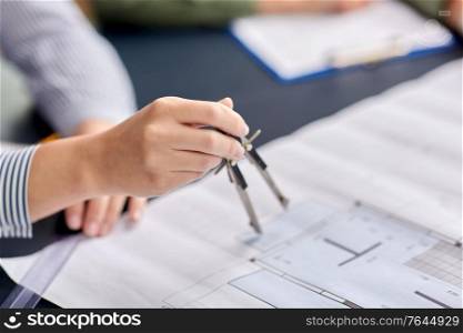 construction business, architecture and building concept - close up of architect with blueprint and drafting compass working at office. architect with blueprint and drafting compass