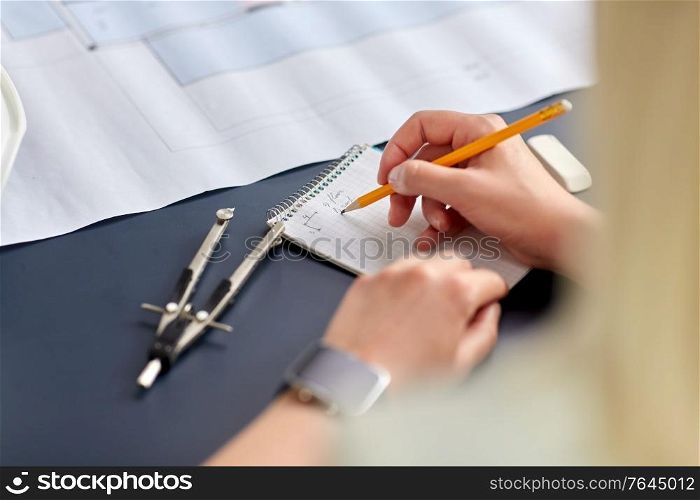 construction business, architecture and building concept - close up of architect with blueprint, notebook and pencil working at office. architect with notebook working at office