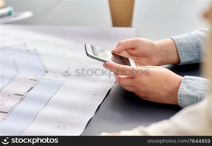 construction business, architecture and building concept - hands of architect with smartphone and blueprint working at office. hands with smartphone and blueprint at office