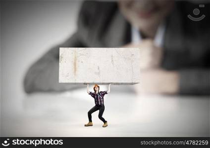 Construction concept. Businesswoman looking at miniature of woman engineer