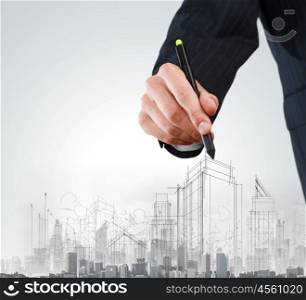 Construction concept. Close up of businessman hand drawing sketches of buildings