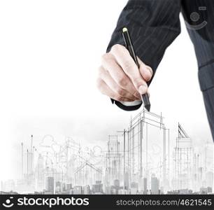 Construction concept. Close up of businessman hand drawing sketches of buildings