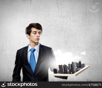 Construction concept. Handsome businessman holding model of modern city