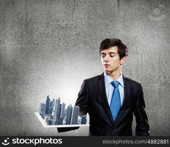 Construction concept. Handsome businessman holding model of modern city