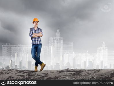 Construction concept. Image of man builder with arms crossed on chest against urban scene