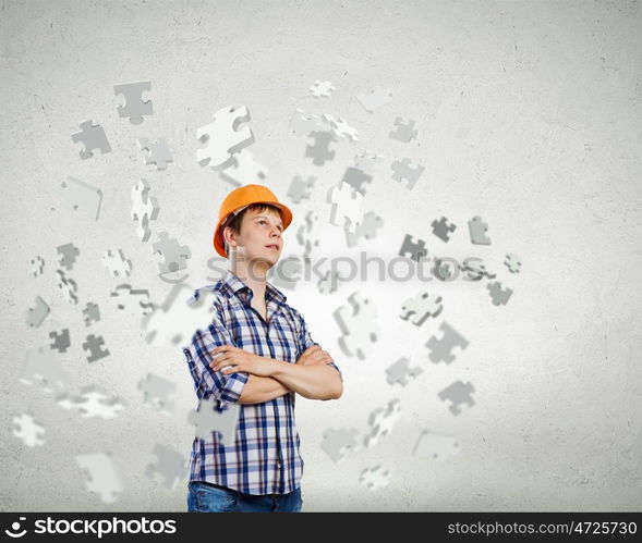 Construction concept. Image of thoughtful man builder with arms crossed on chest