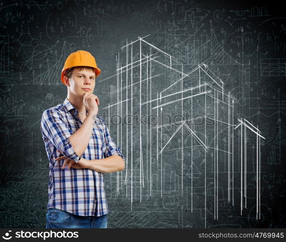 Construction concept. Image of thoughtful man builder with arms crossed on chest