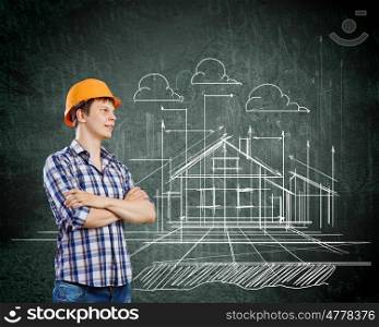 Construction concept. Image of thoughtful man builder with arms crossed on chest