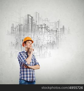 Construction concept. Image of thoughtful man builder with arms crossed on chest