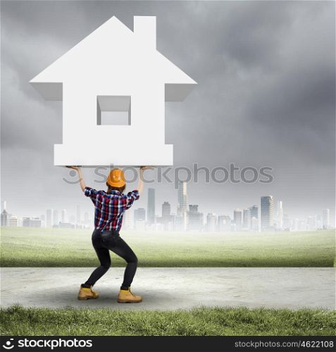 Construction concept. Image of young woman holding house model above head