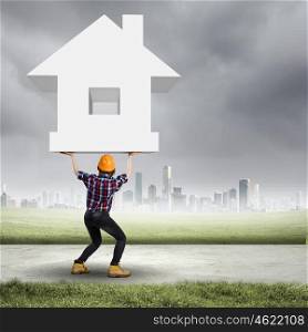 Construction concept. Image of young woman holding house model above head