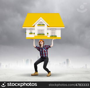 Construction concept. Image of young woman holding house model above head