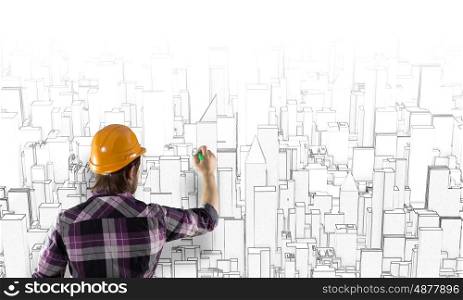 Construction concept. Rear view of engineer drawing project of business district