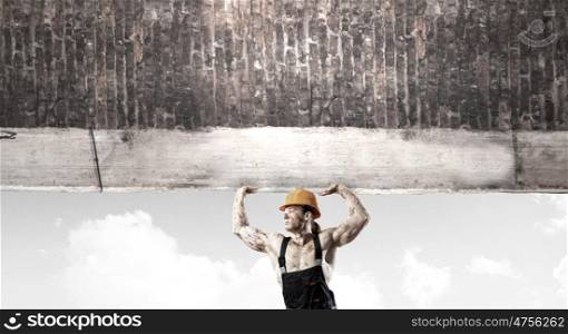 Construction concept. Strong man in uniform lifting wall above head