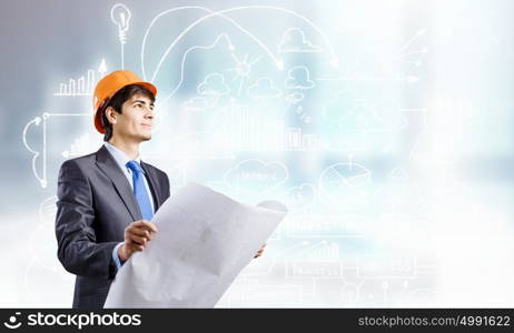 Construction concept. Young man engineer in helmet examining construction project