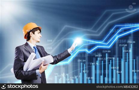 Construction concept. Young man engineer in helmet touching icon of media screen