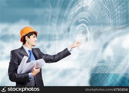 Construction concept. Young man engineer in helmet touching icon of media screen