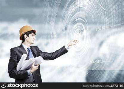 Construction concept. Young man engineer touching icon of media screen