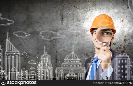 Construction concept. Young man engineer with magnifier against sketch background