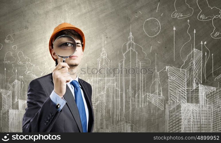 Construction concept. Young man engineer with magnifier against sketch background