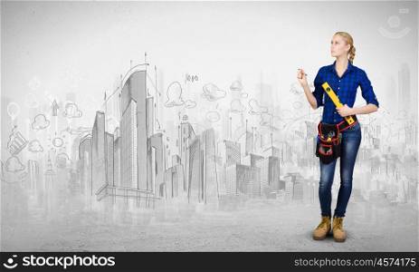 Construction concept. Young woman mechanic with ruler in hand against city background