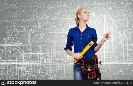 Construction concept. Young woman mechanic with ruler in hand against city background
